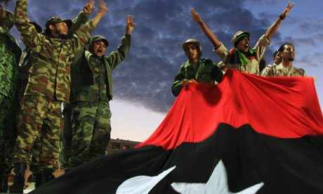 Anti-Gaddafi fighters gesture to the crowds in front of a Kingdom of Libya flag during celebrations in Benghazi on 23 October. Photograph: Esam Omran Al-Fetori/Reuters