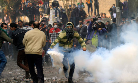 
متظاهر يعيد إلقاء قنبلة مسيلة للدموع على  شرطة مكافحة الشغب خلال مواجهات بالقرب من ميدان التحرير يوم الاثنين. 
Photograph: Khalil Hamra/AP